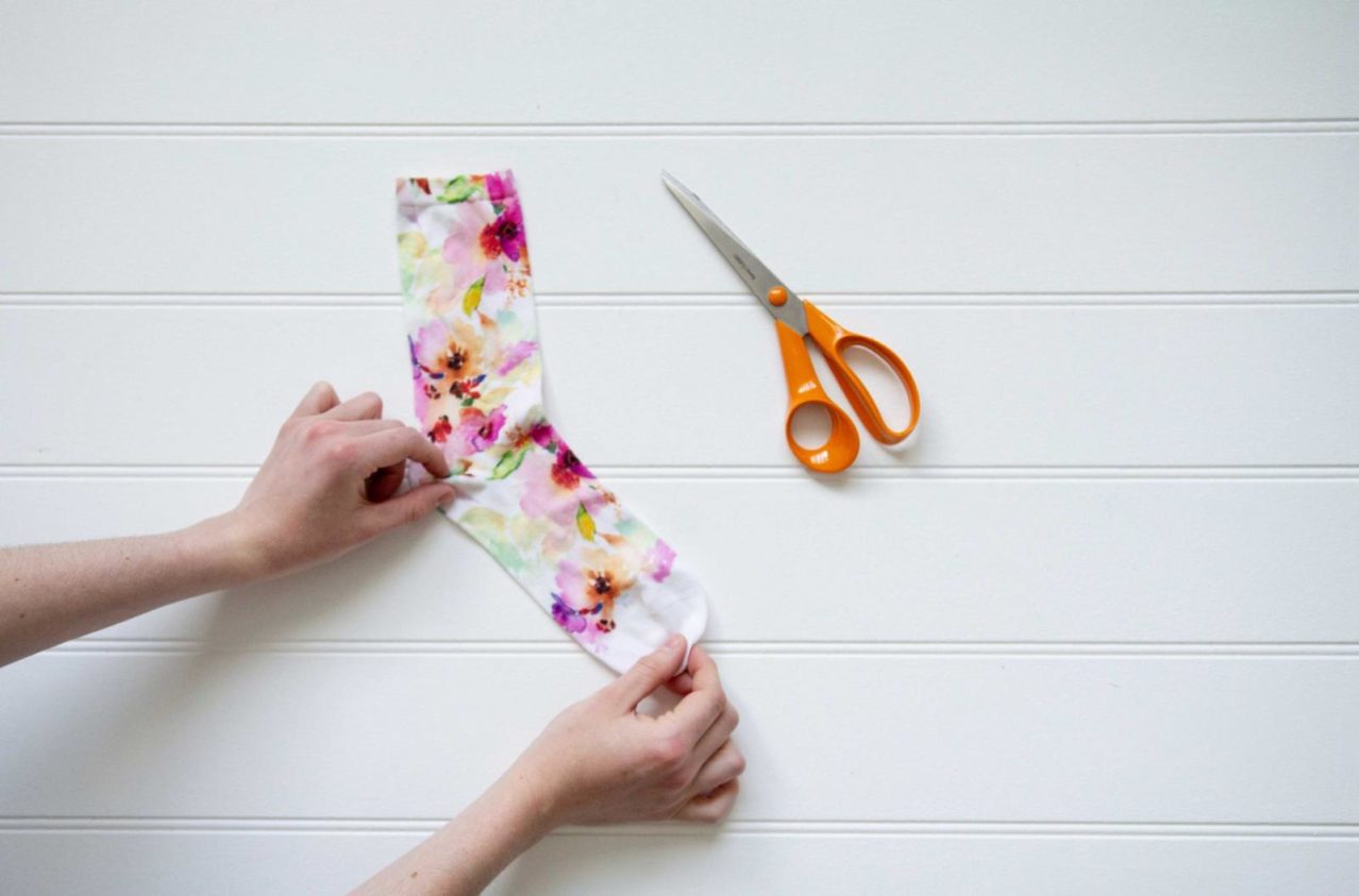 hands holding a floral sock next to scissors